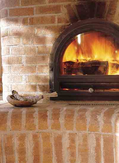 In this Russian stove, evolved from an age-old European design, bricks surround a cast-iron stove to hold the heat inside seven interior chambers. By the time it leaves through the chimney, the heat from the fire has been reduced from 1,800 degrees Fahrenheit to 200 degrees Fahrenheit, and all of that warmth has spread inside the home. “This is a very efficient use of wood,” Tom explains. “One fire a day, and the thing keeps cranking with radiant heat.” Tom and Flame had planned to plaster the fireplace, but while they waited for that to get done, they grew to like the rustic look of the exposed bricks.